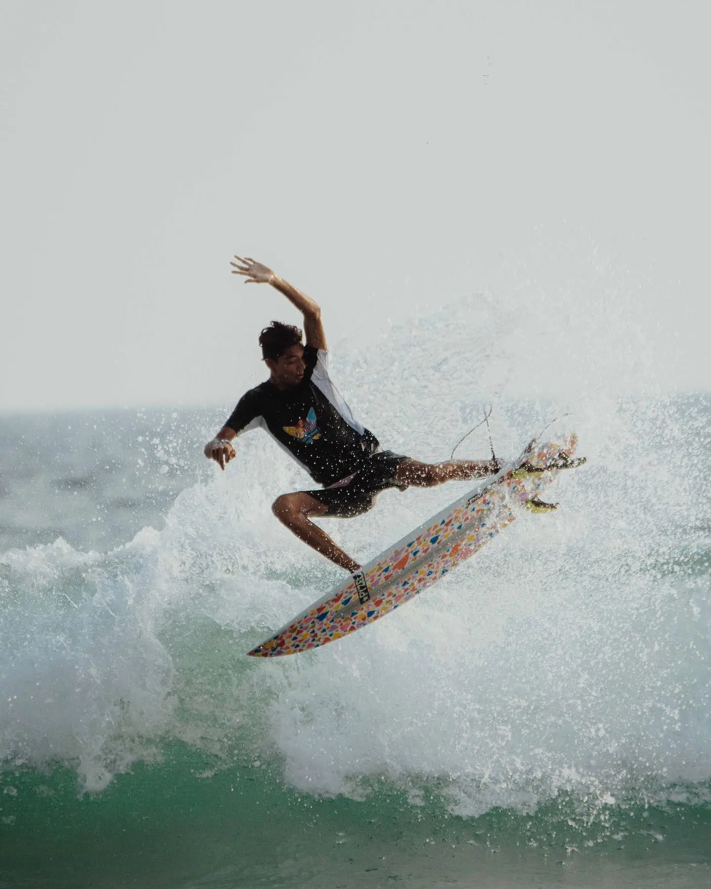 Surfer catching a wave at Unawatuna Beach in Sri Lanka, with turquoise waters, sandy shores, and lush greenery in the background